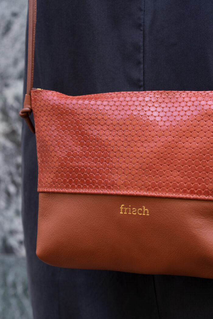 Close up von orangeroter Handtasche von frisch mit goldener Prägung