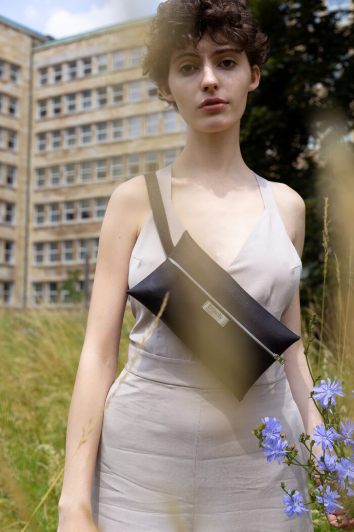 Vegane Gürteltasche aus Kork in schwarz von frisch Beutel getragen von Model auf Blumenwiese