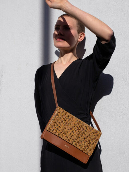 Model trägt schwarzes Kleid und schicke braune Handtasche aus Leder