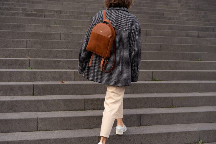 Model läuft auf großer Treppe mit braunem schickem Rucksack