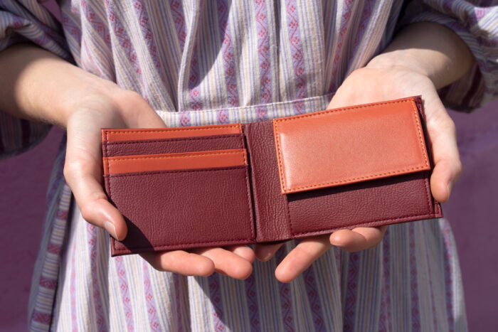 Brieftasche aus Apfelleder in Händen vom Modell in bordeauxrot und orange
