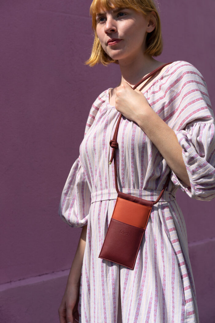 Produktbild einer veganen Handtasche in orange und bordeauxrot gezeigt an Modell