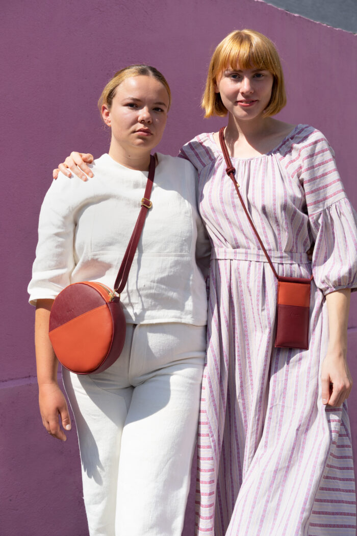 Modelle mit einer veganen Handytasche in orange und bordeauxrot und Runden Tasche