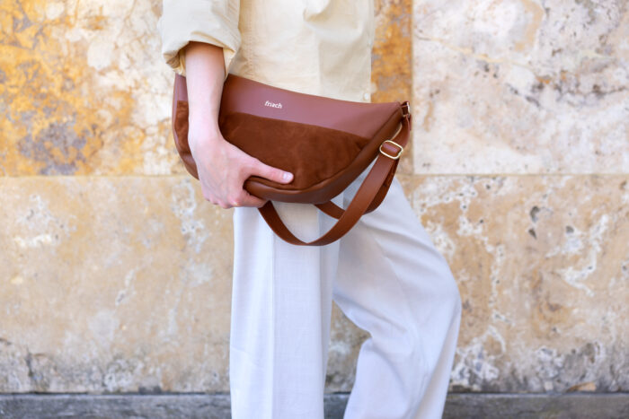 Model mit Handtasche vor marmorierter Steinwand