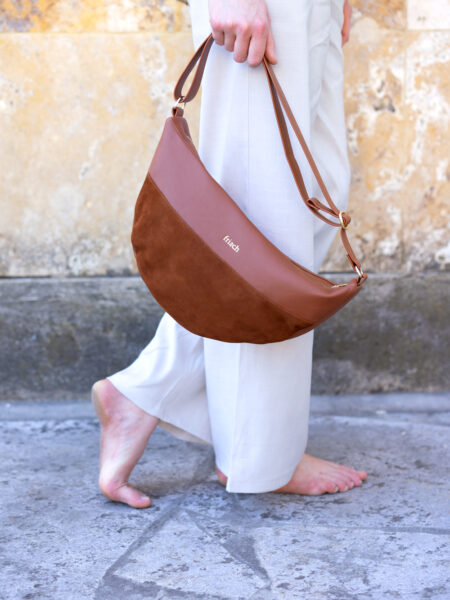 Model mit Handtasche barfuß vor marmorierter Steinwand