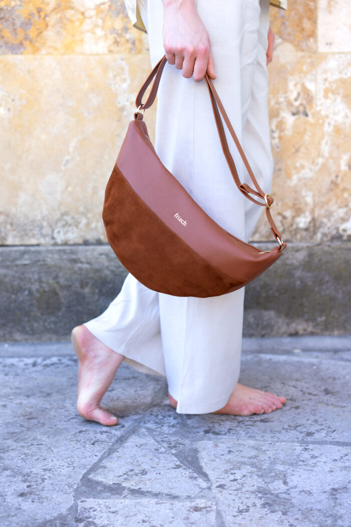 Model mit Handtasche barfuß vor marmorierter Steinwand