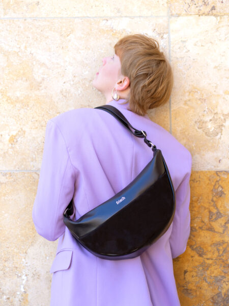 Model mit Lederhandtasche über der Schulter tragend mit fliederfarbenem Blazer