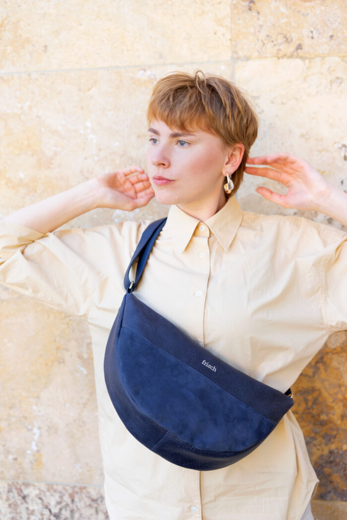 Model mit Lederhandtasche vor marmorierter Steinwand